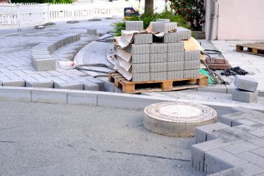 gray paving blocks on ballast, sewer well, construction site of pavement modern granite cobblestone road in city center, roadworks stonework at pedestrian area, concept installation, renovation