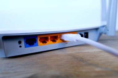 white cable is plugged into the port of Wi-Fi router, modern wireless Router with four non-removable external antennas for better search and signal transmission, concept high speed data processing