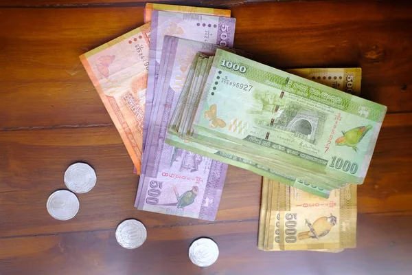 Sri Lanka 'nın ulusal para birimi, kağıt para faturaları Rupi banknotları, ahşap masa üzerindeki paralar, devalüasyon, yüksek enflasyon, seyahat kuru, tatil, tasarruf, bankacılık, vergi ödemeleri