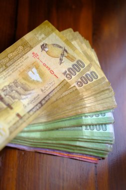 Sri Lanka ulusal para birimi, kağıt para faturaları 5000 Rupi banknotlar, ahşap masa üzerinde sikkeler, devalüasyon, yüksek enflasyon, seyahat, tatil, tasarruf, bankacılık, vergi ödeme kuru