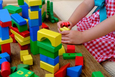 little four year old boy has fun playing at home with wooden blocks building tower under isolation, development of fine motor skills, simulation is the leading activity of children