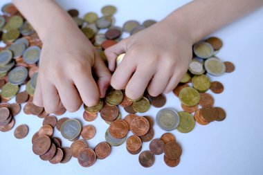 young businessman, child, boy of 10 years old in blue shirt counts coins, sorts out accumulated wealth, savings, pocket money, concept of financial literacy of children, inflation, personal savings