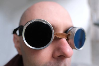 close up part male face, eyes of young pensive man 30 years old in black glasses, steampunk style, concept post-apocalyptic reality, vision examination, treatment of ophthalmic diseases