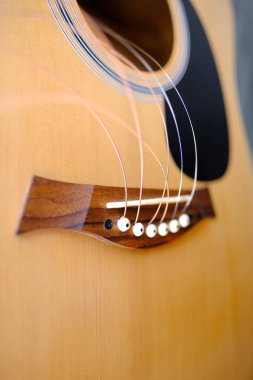 Enstrümanın yakın plan ahşap parçası, akustik gitarın tellerini değiştirmek, serbestçe asılı duran teller, gitar akordu, müzik enstrümanları çalmak için enerjik performanstan koparılmış tellerin değiştirilmesi.