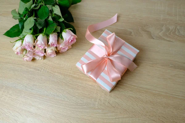 bouquet of white, pink roses, box with gift with satin ribbon, flowers for professional holiday on light table in office, concept of mother\'s, Valentine\'s day, birthday, selective focus
