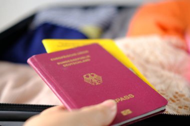 Parlak kadın pasaportunun yakın plan çekimi, covid sertifikası, açık gümüş bavulda katlanmış giysiler, tatil, iş gezisi, heyecan verici bir yolculuk, turizm, seyahat konsepti...