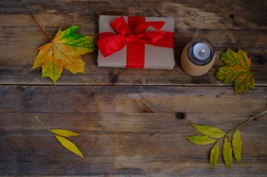 Sarı yapraklar, eski ahşap arka planda kurdeleli hediye, mum yanığı, sonbahar düzlüğü, sonbahar konsepti, tasarımcı için arka plan