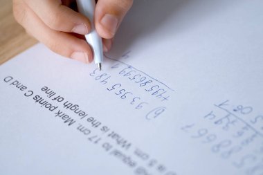 çocuk, sağ elini kullanan okul çocuğu, rakamları eklemek gibi zor bir işi tereddütle çözer, 5. sınıf öğrencisi not defterine numaraları yazar, matematiksel yeteneklerin gelişimi, eğitim kavramı