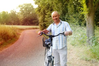 Bisiklet gülümseyen yaşlı, olgun bir adam, bisiklet meraklısı, doğayı izleyen, basit zevklerin tadını çıkaran, son sınıfların farkındalığını besleyen, hayatın anlarını besleyen.