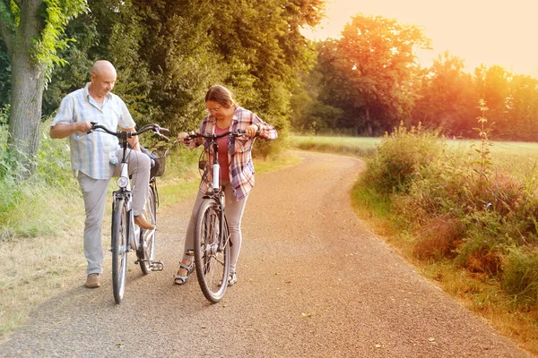 elderly, mature man and woman with bicycles, happy couple rides together in park, bicycle tour of natural beauties, cherishing life\'s moments