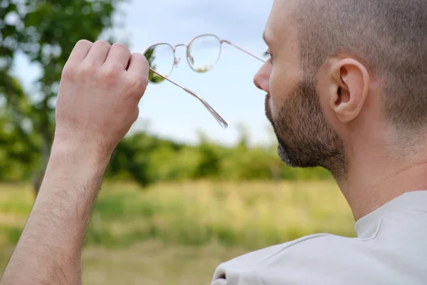 Closeup Jovem Carismático Homem Verifica Óculos Ouro Limpeza Transparência Lentes — Fotografia de Stock