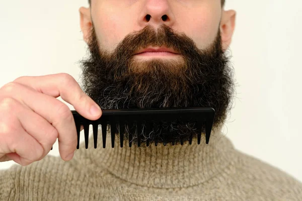 stock image close-up of male face, young bearded and mustachioed man, guy with 25 - 30 years combs his thick beard, concept of mustache and beard stubble care products, hairline hygiene on lower part of face