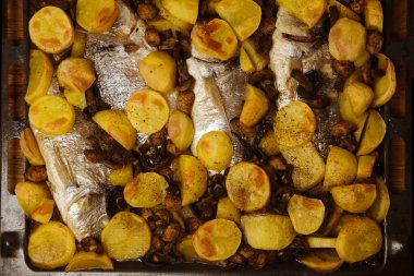 Fırında pişirme tepsisinde lezzetli köri soslu balık, fırında patates, mantar, baharat, abur cubur konsepti, geleneksel aile partisi, balık yemekleri.