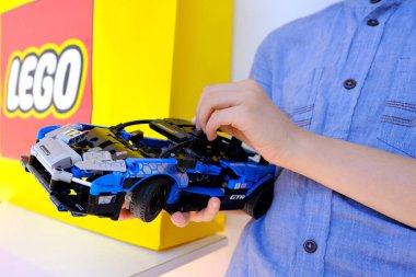 çocuk, çocuk 10 yaşında Lego parçalarından mavi araba monte eder, eğitim inşaatçısı, konsept geliştirme iyi motor becerileri, eğitim sabrı, mantık, arka planda lego logosu, Frankfurt - 27 Temmuz 2022