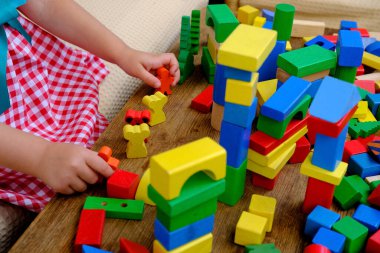 smart little child, girl 3 years old playing with educational toy, wooden geometric figures, blocks, kindergarten games, concept of childhood, earlier child development, creativity, early training
