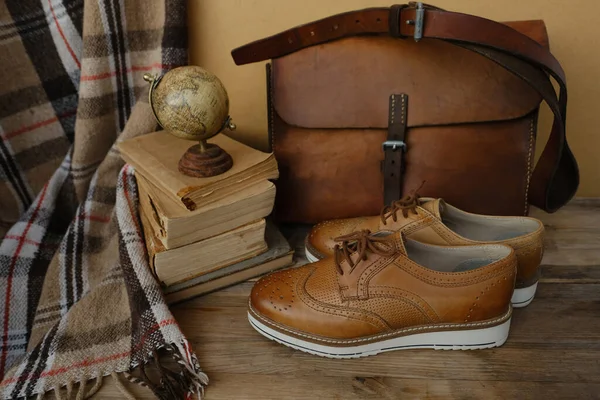 closeup old things, stack of vintage books, globe, shoes, leather military satchel on table, checkered grandmother\'s plaid, concept of family tree, home archive, genealogy, memory of ancestors