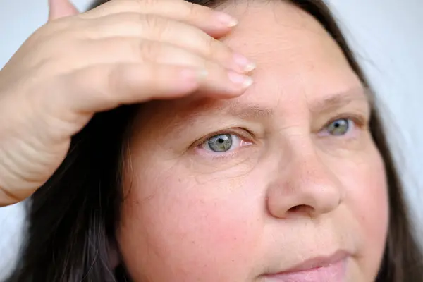 閉じられた女性の顔の女性50歳 皮膚の腫瘍をチェックします ヒアルロン酸を適用します 顔に保湿剤 アンチエイジング肌の若返り セルフケアと全体的な顔の外観を強化 — ストック写真