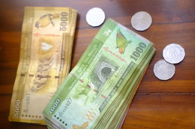 Sri Lanka 'nın ulusal para birimi, kağıt para faturaları Rupi banknotları, ahşap masa üzerindeki paralar, devalüasyon, yüksek enflasyon, seyahat kuru, tatil, tasarruf, bankacılık, vergi ödemeleri