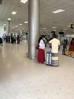 Havaalanı binasından giriş yapmayı bekleyen Asyalı havayolu yolcuları, elektronik skorbordda uçak uçuşları, lobi havaalanı, modern salon, seyahat, Colombo, Sri Lanka - 9 Ekim 2022