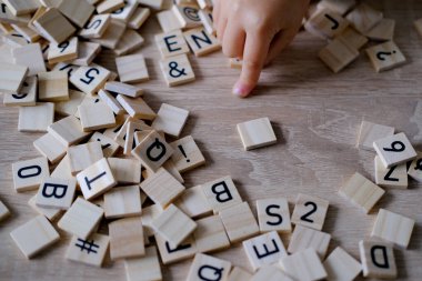 Eller yakın, küçük çocuk 3 yaşında tahta alfabe blokları oynuyor, harflerden kelimeler uyduruyor, disleksi farkındalığı, öğrenme güçlüğü, insan beyni gelişimi, mutlu çocukluk, seçici odaklanma