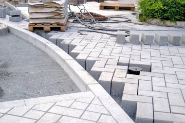 gray paving blocks on the ballast, side view, construction site of pavement modern granite cobblestone road in city center, roadworks stonework at pedestrian area, concept installation, renovation