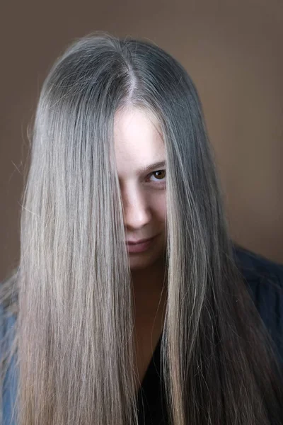 紧贴着年轻女人的部分脸 29岁的可爱女孩 有着长长的棕色头发 监视的概念 梳理头发 化妆品护发程序 — 图库照片