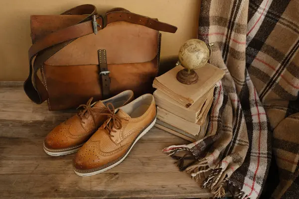 closeup old things, stack of vintage books, globe, shoes, leather military satchel on table, checkered grandmother\'s plaid, concept of family tree, home archive, genealogy, memory of ancestors