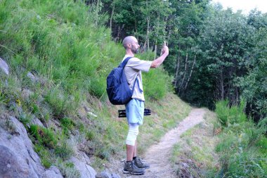 Genç adam, sırt çantalı bir turist güzel manzaralı, kısa bir dinlenme, doğa izleme, konsept yaz tatili, seyahat, rahatlama ve keyif.