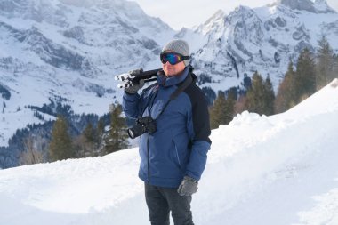 Kameralı yaşlı bir adam, dağ yürüyüşçüsü kış manzarasına hayran, spor konsepti, sağlıklı yaşam tarzı, kış etkinliği, güzel kış doğal manzarası, kışın beyaz ormanda yürüyor.
