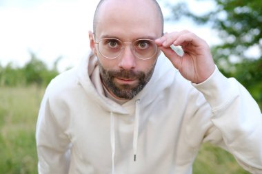 30-35 yaşlarında bir adam mesafeye bakar, zayıf görür, şaşı olur, gözlük takar, erkek yüzünü kapatır, görsel netlik ve miyoplara hitap eder, görüş düzeltmesi yapar.