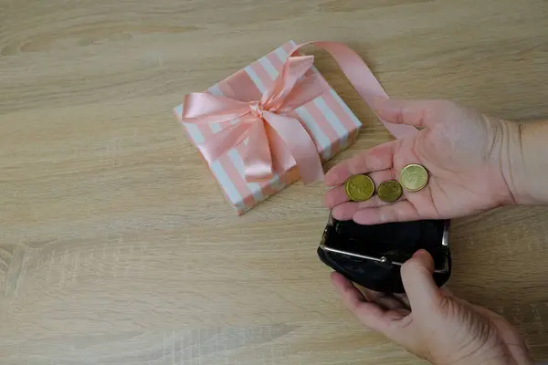 white, pink box with gift, female hands holding euro cents on light table in office, concept of expensive gift for holiday, Valentine\'s day, birthday, christmas gift, selective focus