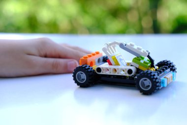 Manipülatörlü transformatör araba, lego parçalarından bir araya getirilmiş, bokeh ağaçlarının güzel yeşil arka planı, iyi motor becerilerin gelişimi konsepti, yaratıcılık, Frankfurt - 8 Haziran 2022