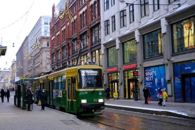 İnsanlar kış caddesi boyunca Helsinki şehrinde yürüyor, modern yeşil tramvay raylarda, konsept tatil alışverişi, yolcu trafiği, turistler, Helsinki, Finlandiya - 8 Ocak 2022