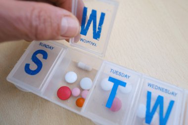 Tıbbi kapsüller, haplar, ilaç kutusunda vitaminler, yakın çekim erkek elleri plastik düzenleyiciyi haftalık olarak tutuyor, konsept düzenli ilaç alımı, ilaç dozajı, hasta alımının düzenlenmesi