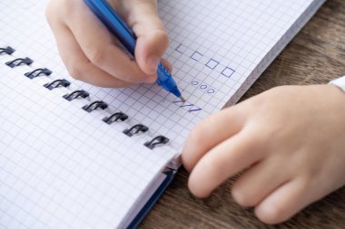 Çocuğun el yazısı kareli defterle, anaokulu için el yazısı alıştırması, anaokulu öğrencileri için el yazısı pratiği
