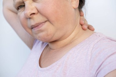 Yaşlı 55 'li yaşlarda, beyaz kadın, boynu ağrıyor, kadın sağlığı konsepti, omurgalar arası fıtık diskleri, artrosis, miyofasyal sendrom, omurgalar arası eklemlerde fonksiyon bozukluğu
