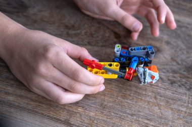 Çocuk ellerine yakın çekim, parçalardan inşaat, robot dağcı figürü, Mühendislik Eğitimi, Oyun yoluyla öğrenme
