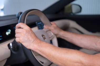 Nio elektrikli arabanın direksiyonunda, erkek eller sürücü koltuğunda, modern yolcu vagonunda, gösterişli iç mekan kontrol tekerleği, vites kolu, ön cam ve ön panel gibi.