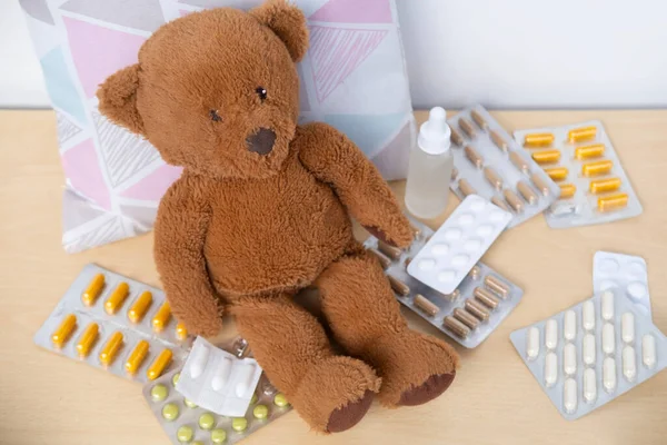 teddy bear sick, surrounded by scattered medicines and pills, health, care and treatment children through soft toy, medical therapy and pediatrics