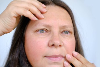 Dudaklarında nazik bir gülümsemeyle mutlu 50 yaşında bir kadın, insan cildinde yaşla ilgili değişimler, olgun yaş kavramında psikolojik refahın korunması, olgunluk ve aktif yaşam ve neşeli bir hayat.