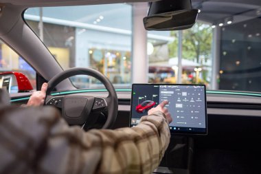 Tesla test sürüşü, genç adam, potansiyel alıcı, arabanın içinde oturur, aracın sistemlerini test eder, otomotiv endüstrisindeki son teknolojileri, çevresel sürdürülebilir, Frankfurt - 9 Kasım 2023