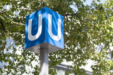 U harfi, metro tabelası toplu taşıma istasyonunun girişinin yanındaki direkte, yer üstünde metro yolculukları, yolcuları taşımak, Metro toplu taşımacılığı, Sokak Güvenliği, Şehir Hareketi