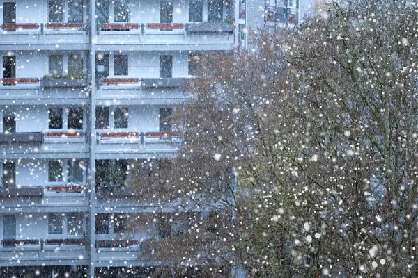 snowing outside against backdrop of multi-story building, urban landscape, winter weather conditions and snowfall, video shooting from inside of room, City Living in Winter, Urban Lifestyle