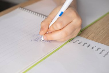 Ödev yapan okul çocuğu, İngilizce kopyalayan İngilizce, not defterine yazan çocuk, İngilizce dil alıştırmaları, edinim, okul ortamında sözcük dağarcığı oluşturma, iki dilli eğitim içeren ödevler