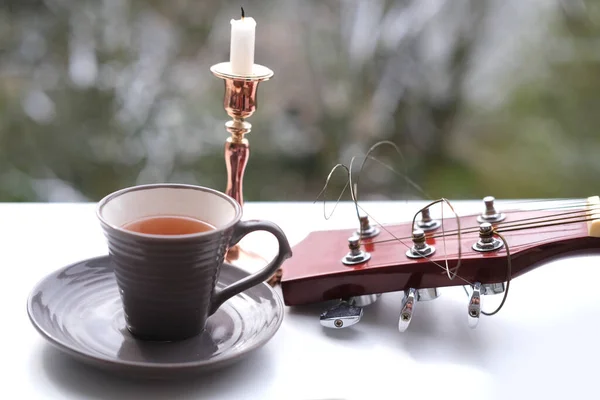 table in the garden, tea, coffee in a mug, close-up of a neck guitars, candle is in a candlestick, concept of an outdoor tea party, good weather, a cozy mood, nostalgia mood