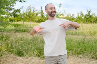 30-35 yaşlarında, açık tişörtlü, şık gözlüklü, doğal arka planda, Gençlik Kültürü ve Stereotipli, genç nesil, giysiler, aksesuarlar, açık hava aktiviteleri...