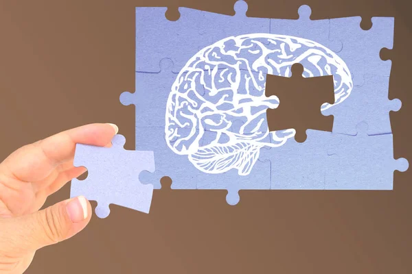 cardboard puzzle piece in female hand, Brain white jigsaw puzzle with copy space on background, missing piece of brain puzzle, mental health, memory