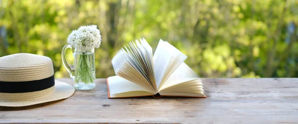 paper book, bouquet of wild garlic flowers on old wooden table in garden, blurred natural landscape background with green foliage, Ecology concept, nostalgia knowledge, education, energy of nature