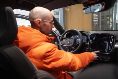 Genç adam iç mekanı, Volvo xc40 'ın kokpitini, dijital paneli, direksiyondaki aletleri, EV teknoloji otomotiv endüstrisini, Frankfurt' taki çevre aracını inceliyor - 22 Ocak 2024