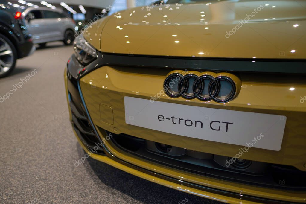 Front Luxury Electric Car Audi e-tron GT, Logo on cap, yellow four-door coupe in showroom, Automotive Innovation in automotive industry, Future Mobility show in Frankfurt, Germany - January 22, 2024